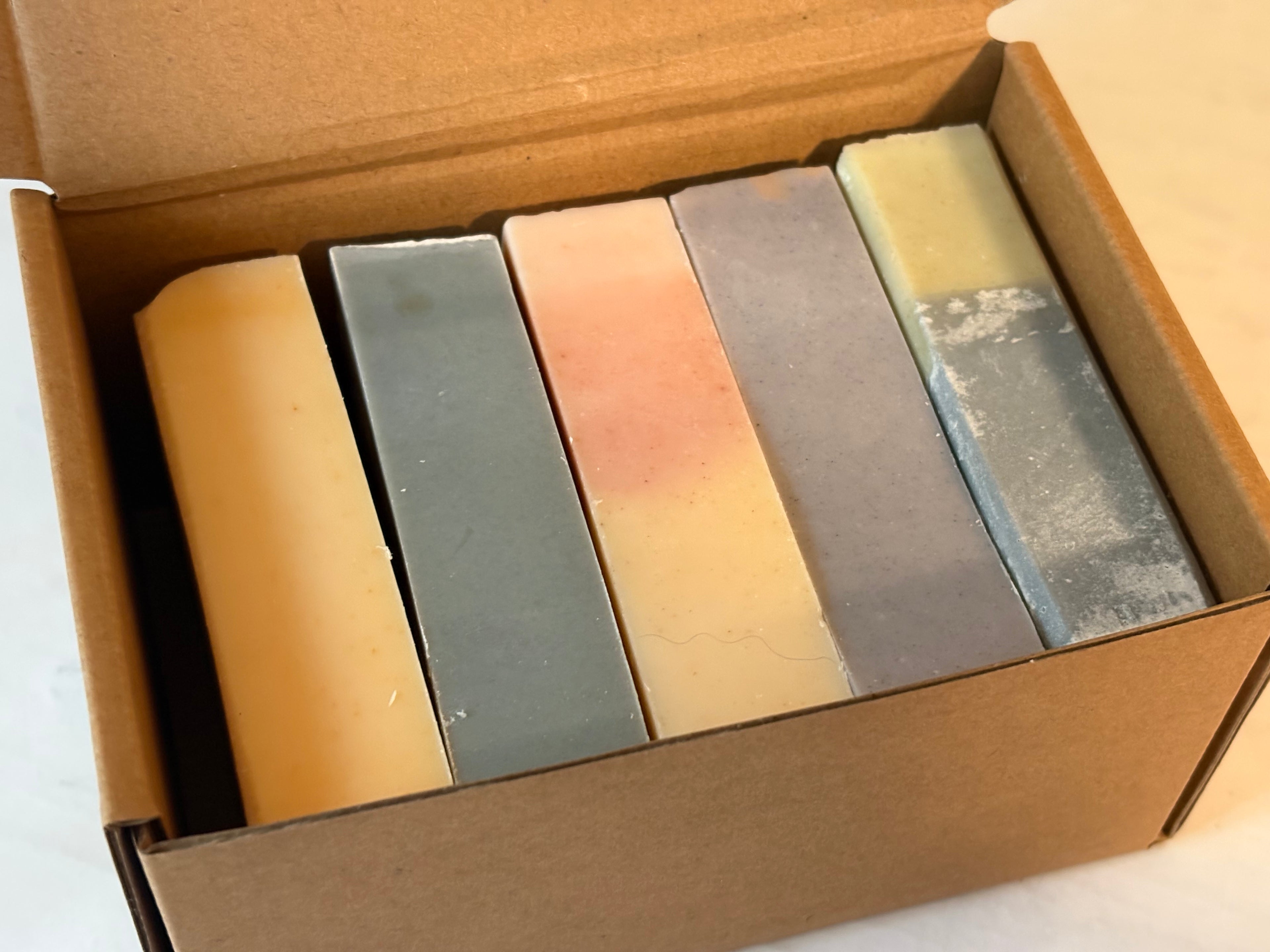 Five bars of handmade soaps from West Grove Soaps in a cardboard box