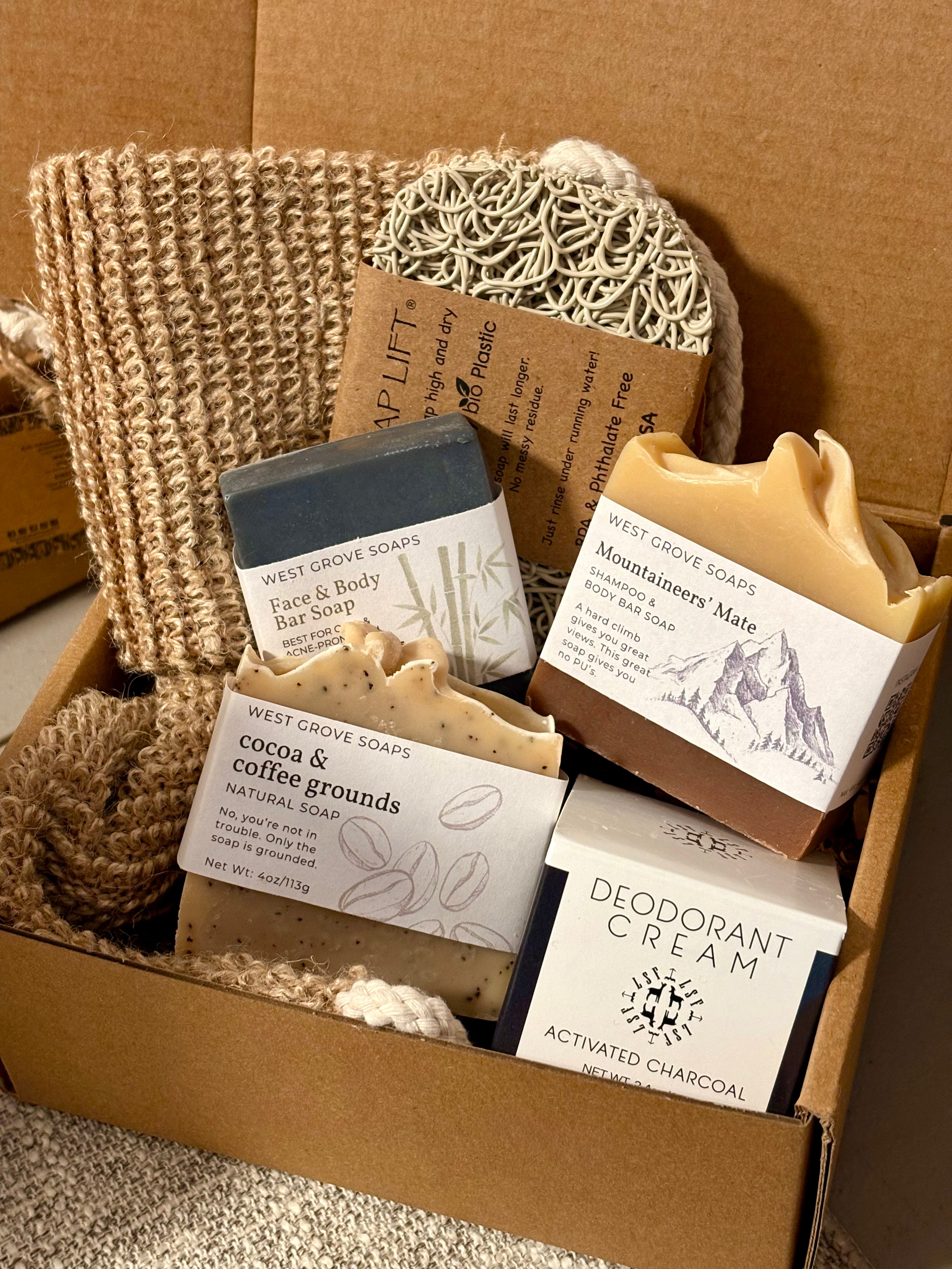 Box of natural skincare and body care products including soap bars and cream.
